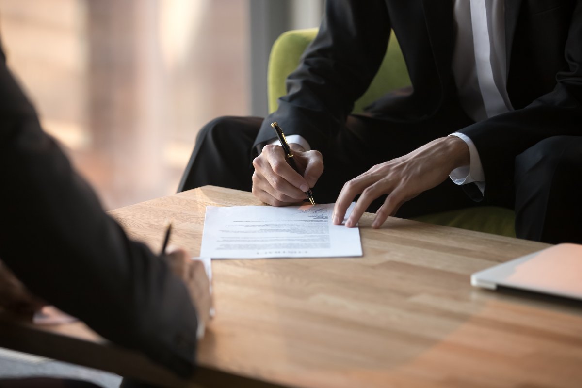 Business professionals signing paperwork.