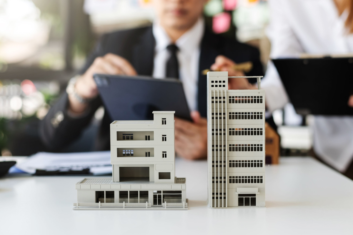 Business owner using tablet with model business real estate building in front