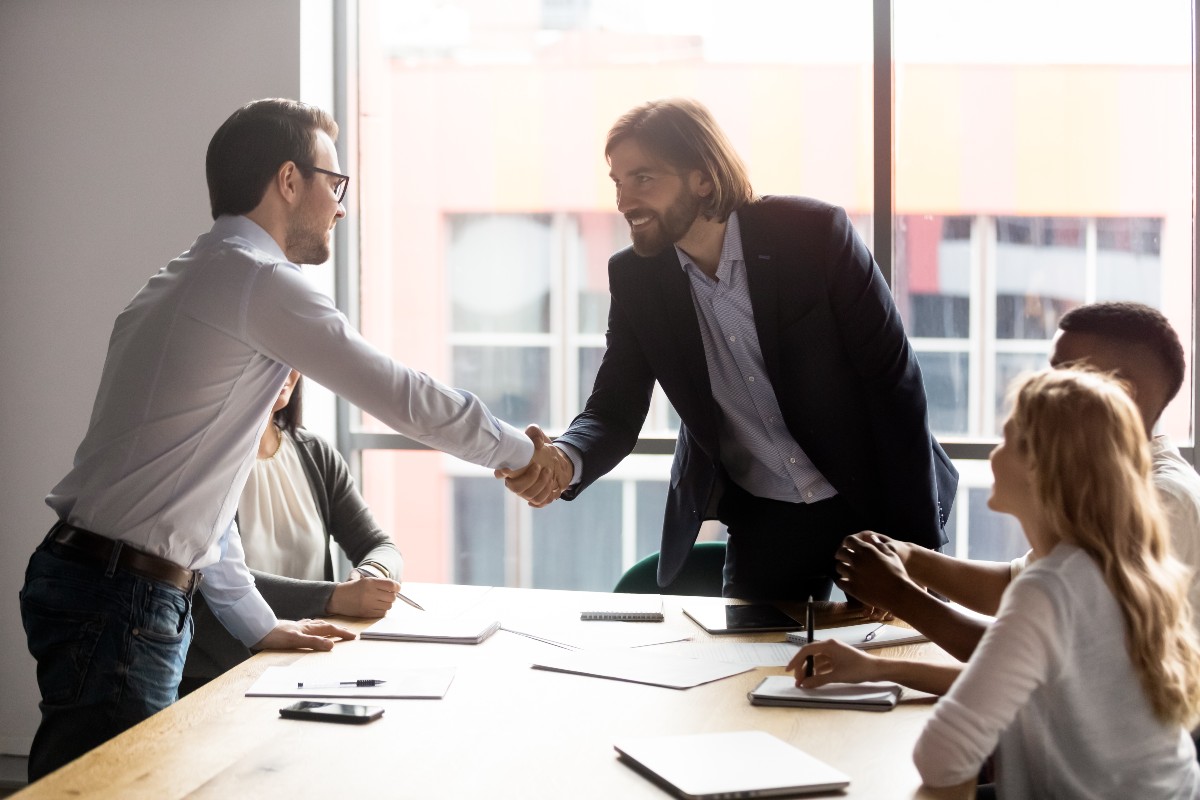 Business partners shaking hands in group meeting