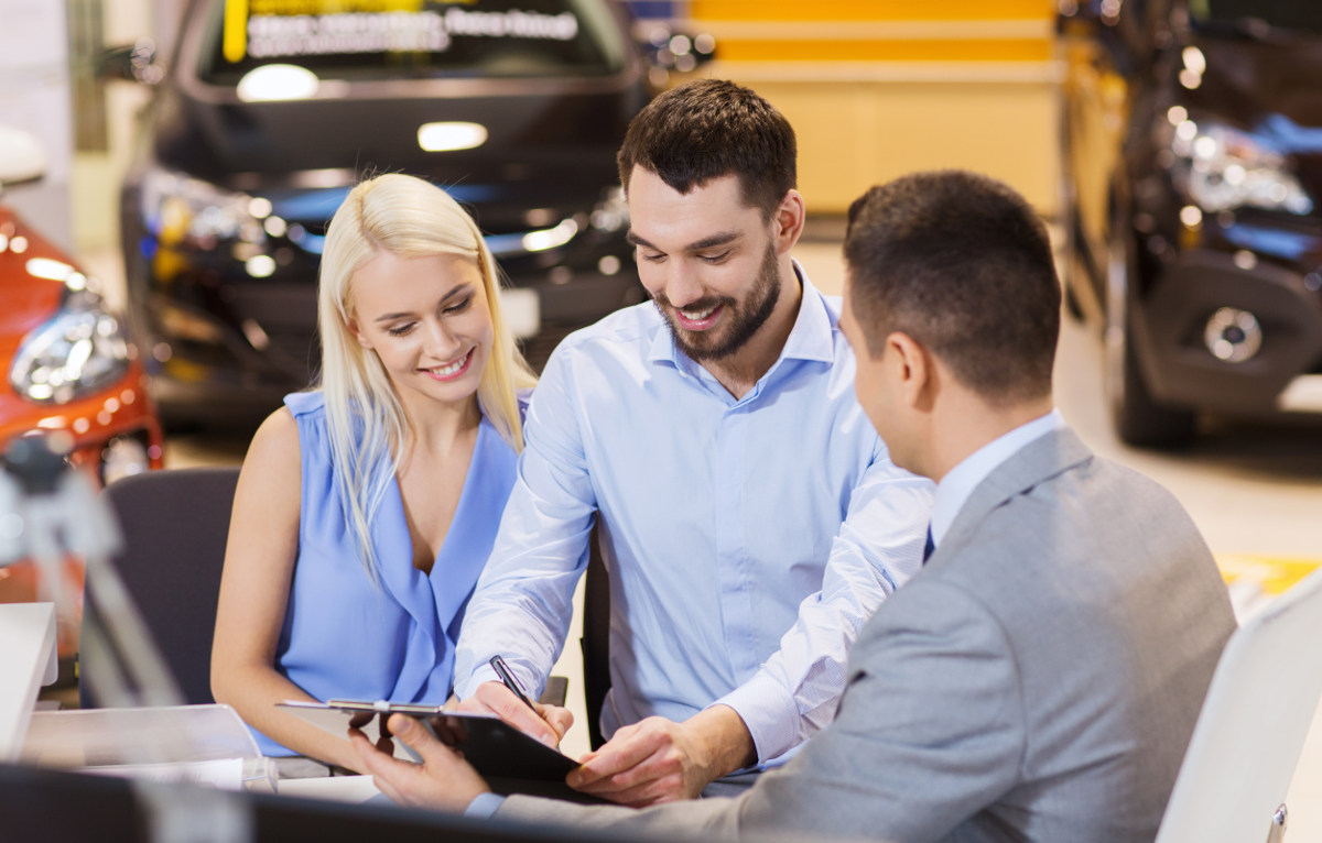 Man filling out auto loan paperwork at dealership.