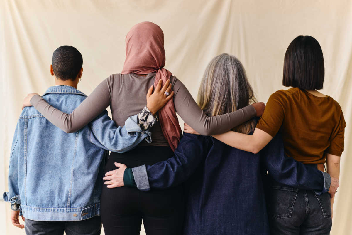 Rear view of four women with arms around each other