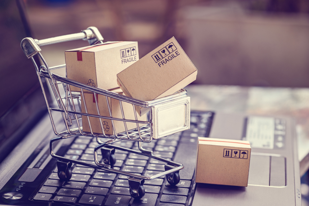 Mini shopping cart full of boxes on top of laptop keyboard