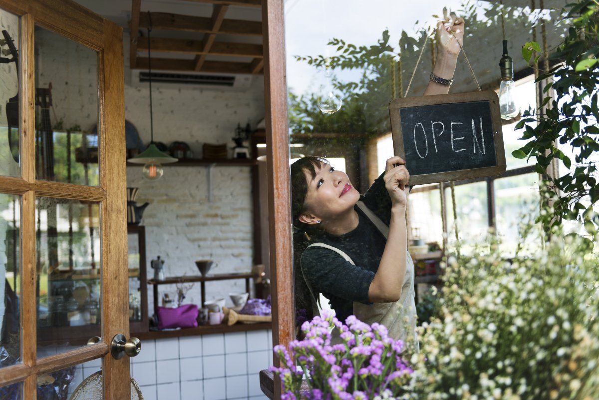 Small business owner hanging "open" sign in storefront window