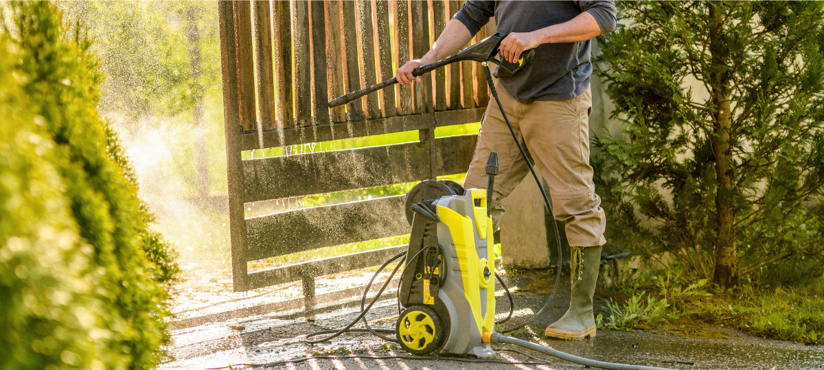 Man watching a gate with a pressure washer.