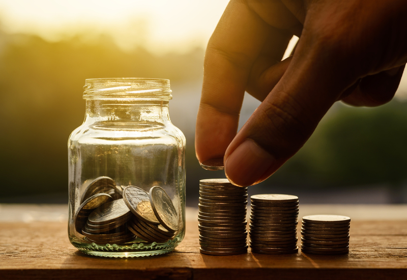 Person saving up money in a small glass jar.