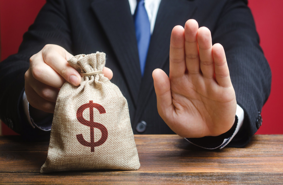 Man holding a small bag of money with one hand and using his other hand to indicate that the money is not available.