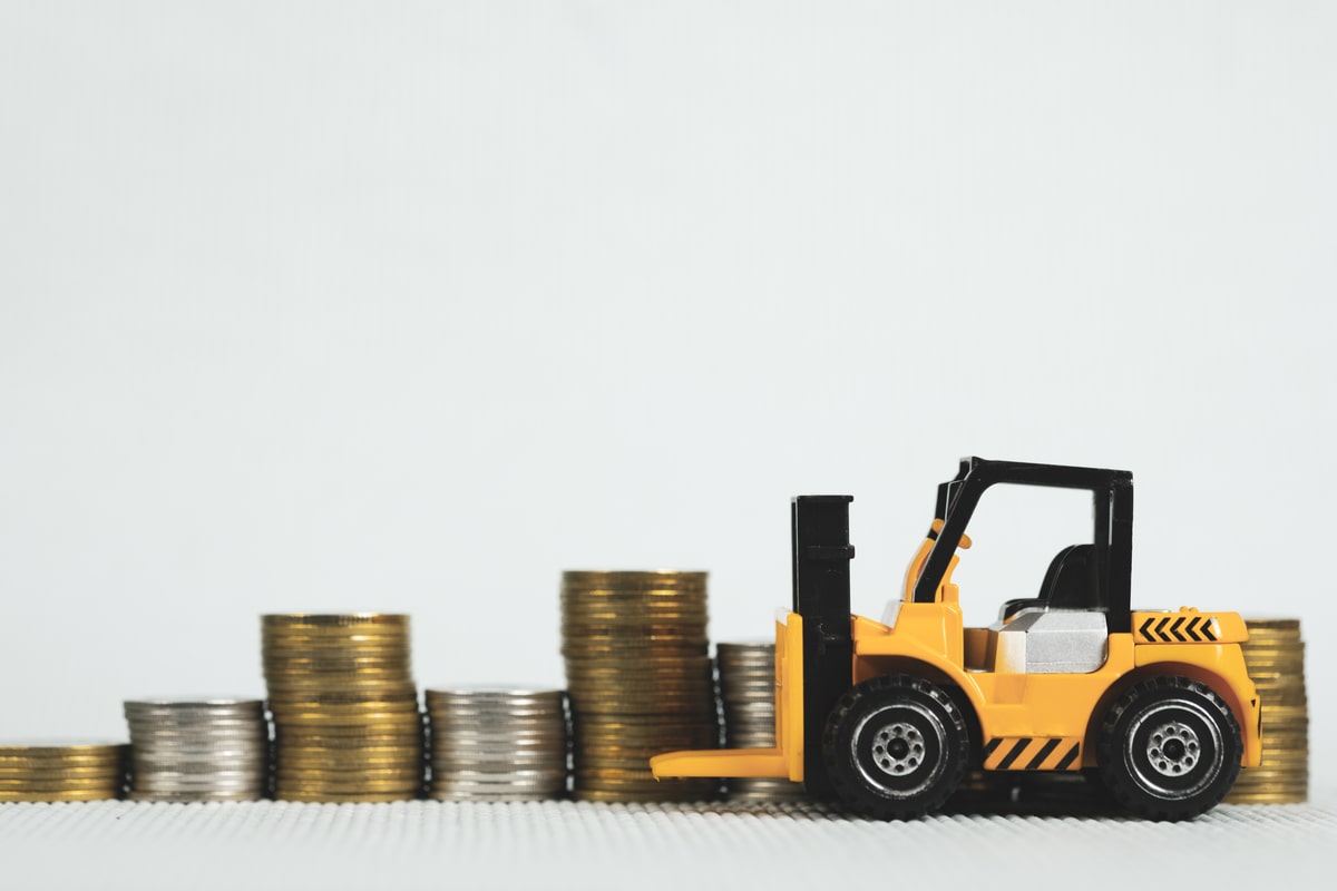 A toy forklift next to stacks of coins.