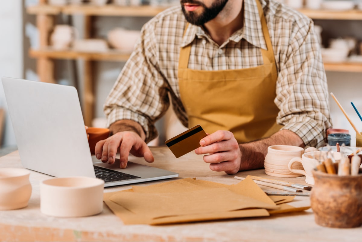 Worker using a credit card to buy something from his computer.